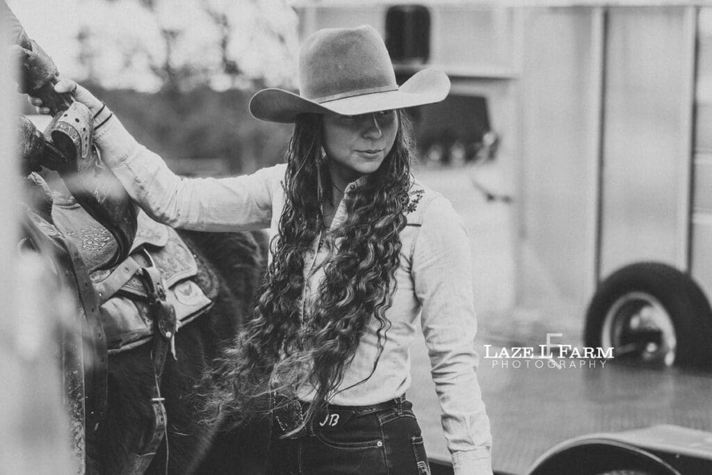 cowgirl saddling her horse