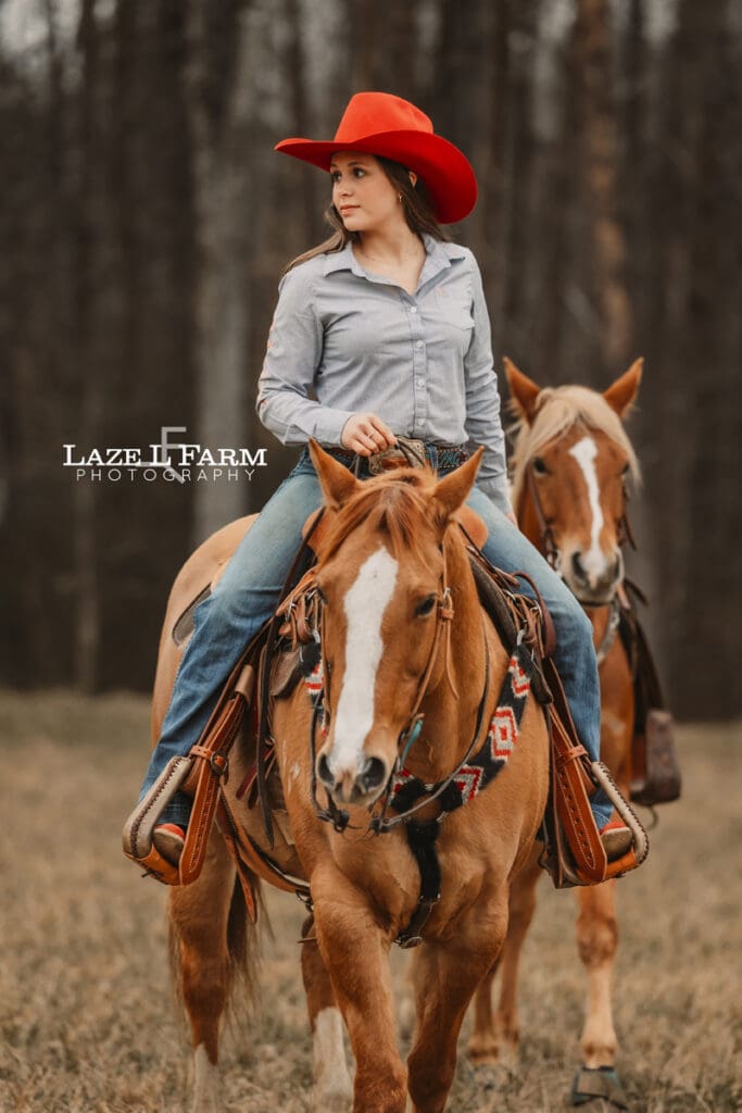 cowgirl riding her horse leading another one