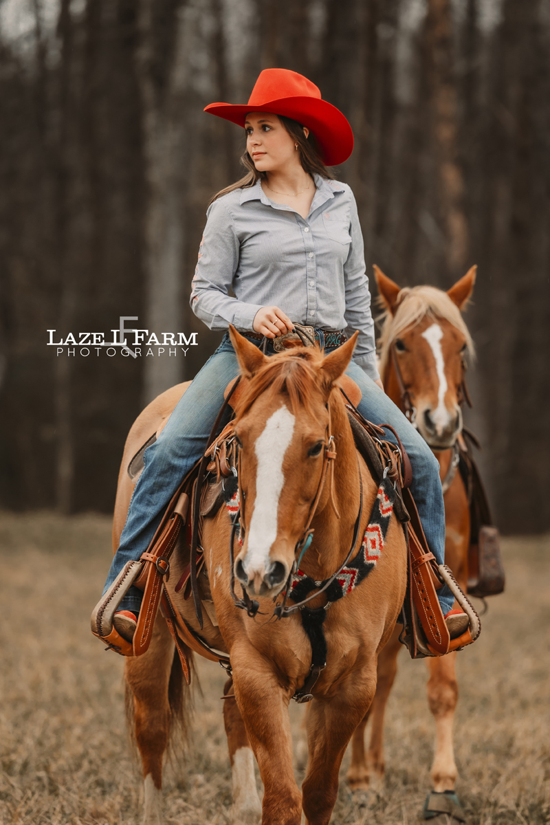 cowgirl riding her horse leading another one