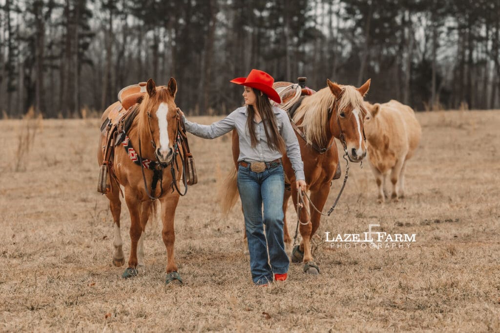 cowgirl walking with her two horses