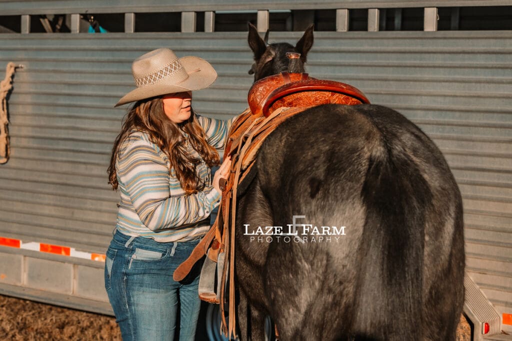 cowgirl saddling horse