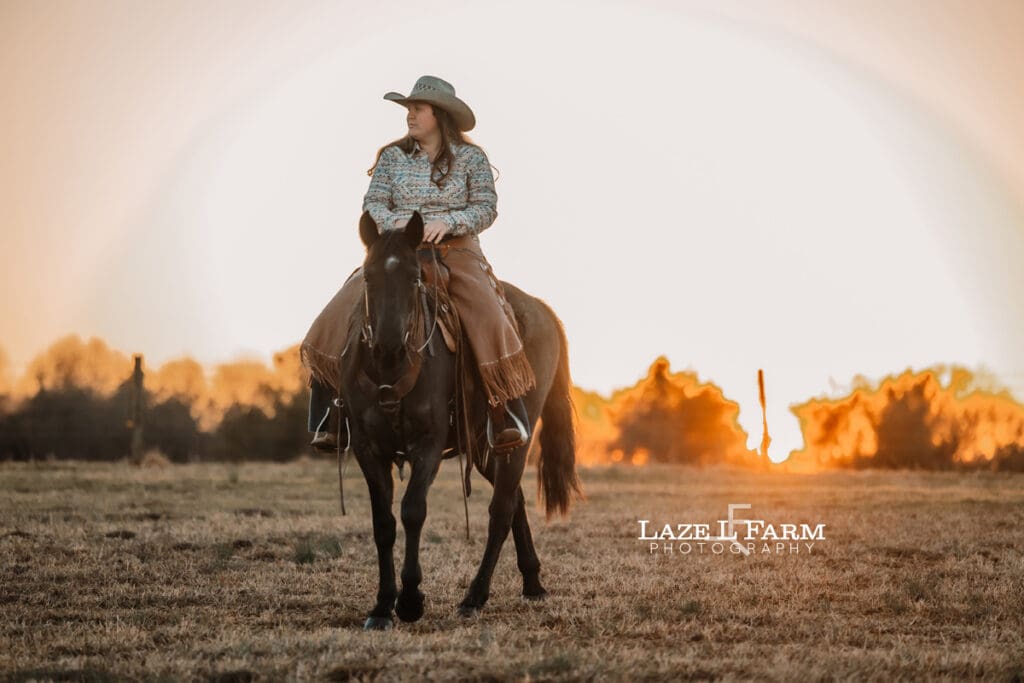 cowgirl riding her horse at sunset