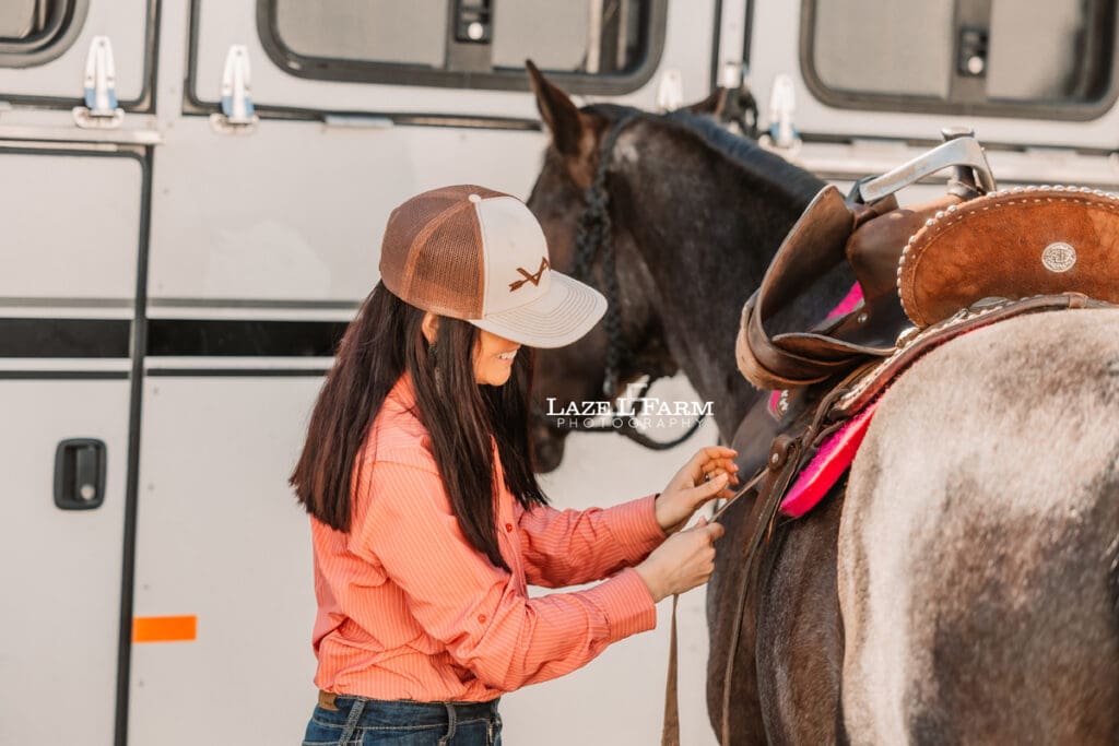 cowgirl saddling her horse
