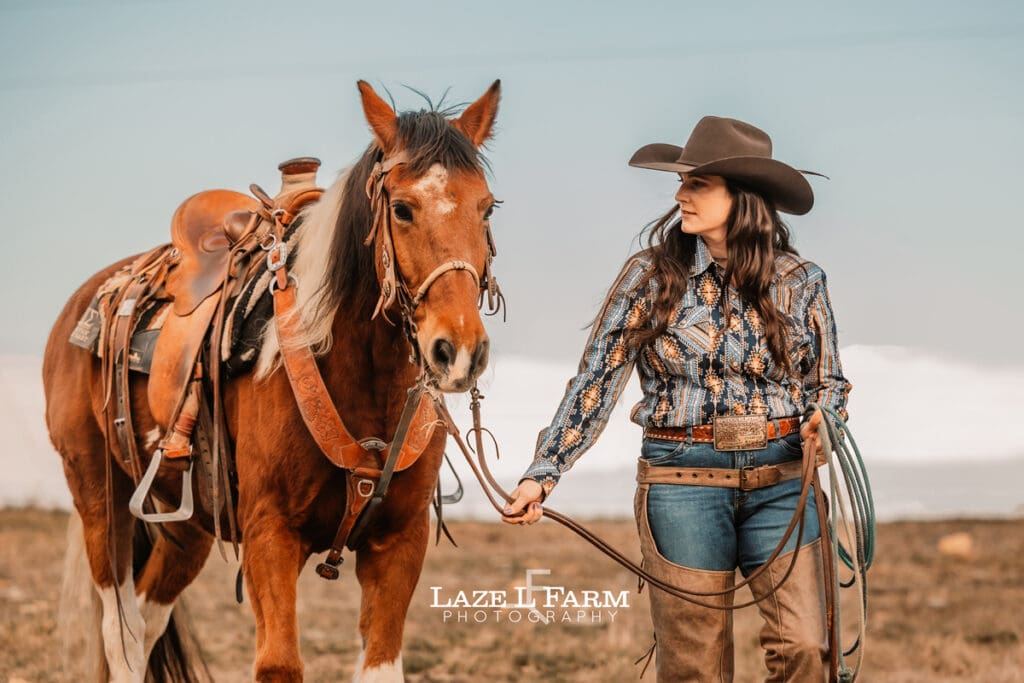cowgirl standing beside her horse