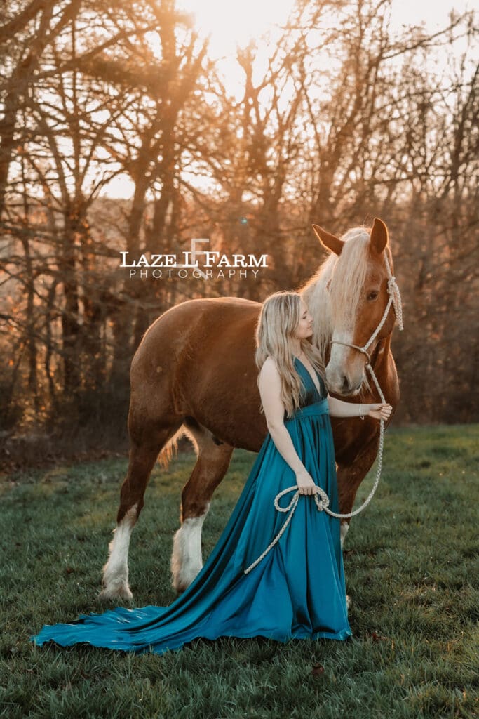 girl in a dress standing beside a draft horse
