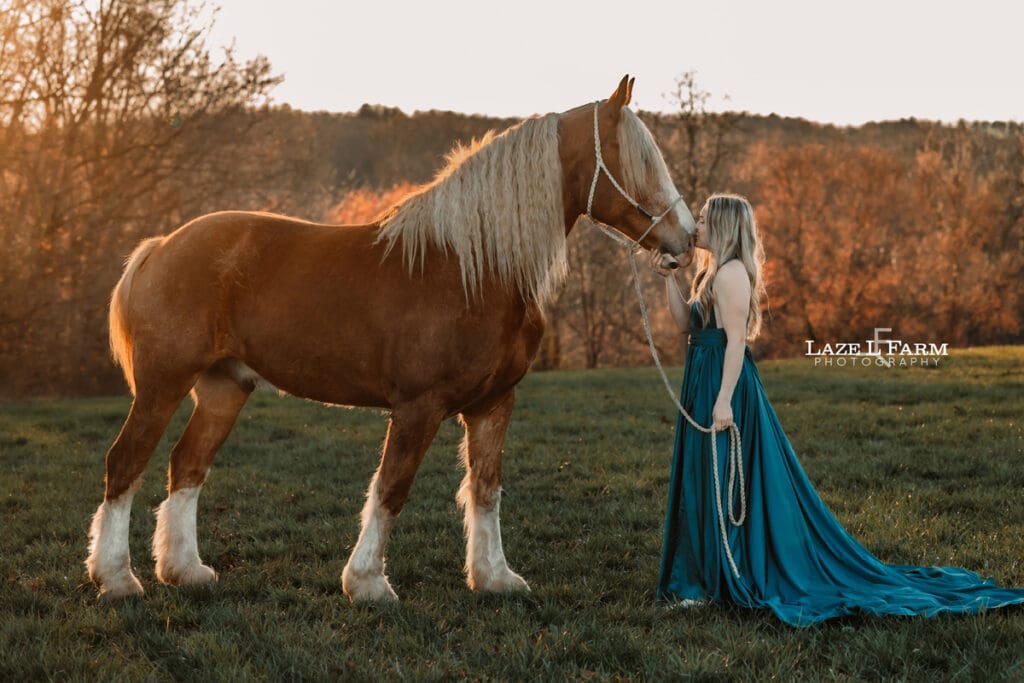 girl in a dress standing beside a draft horse