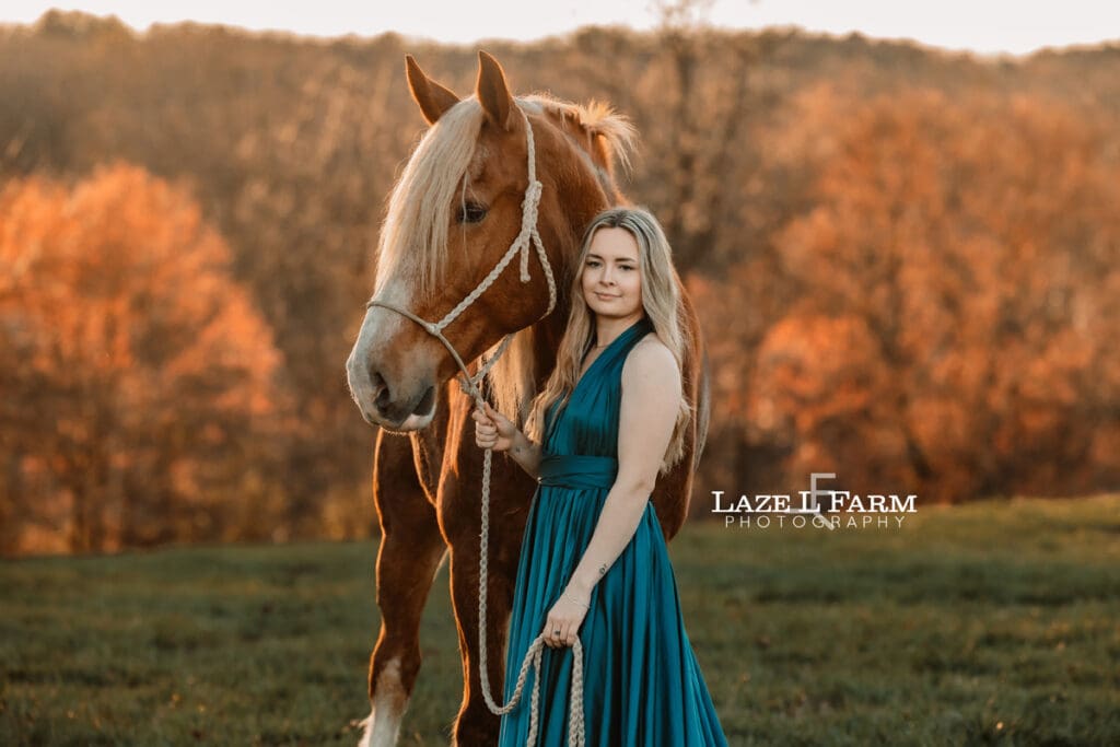 girl in a dress standing beside a draft horse