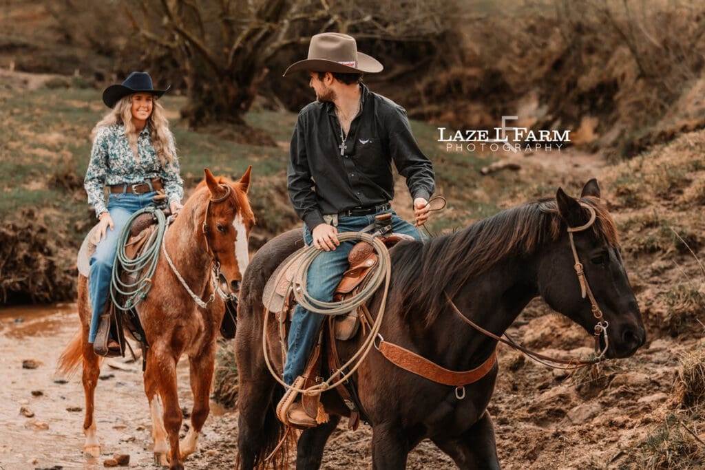 western couple riding their horses through the creek
