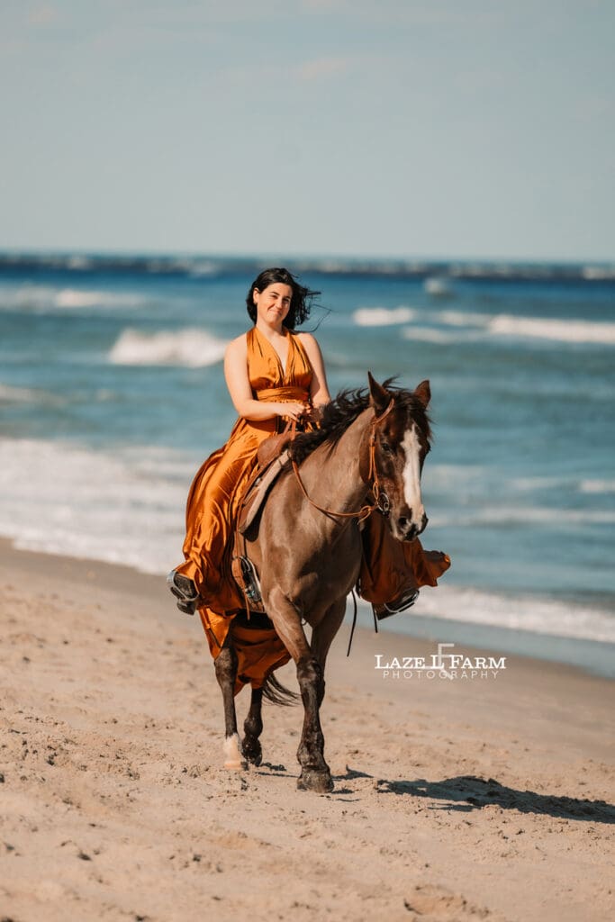 cowgirl on the beach with her horse in a flying dress