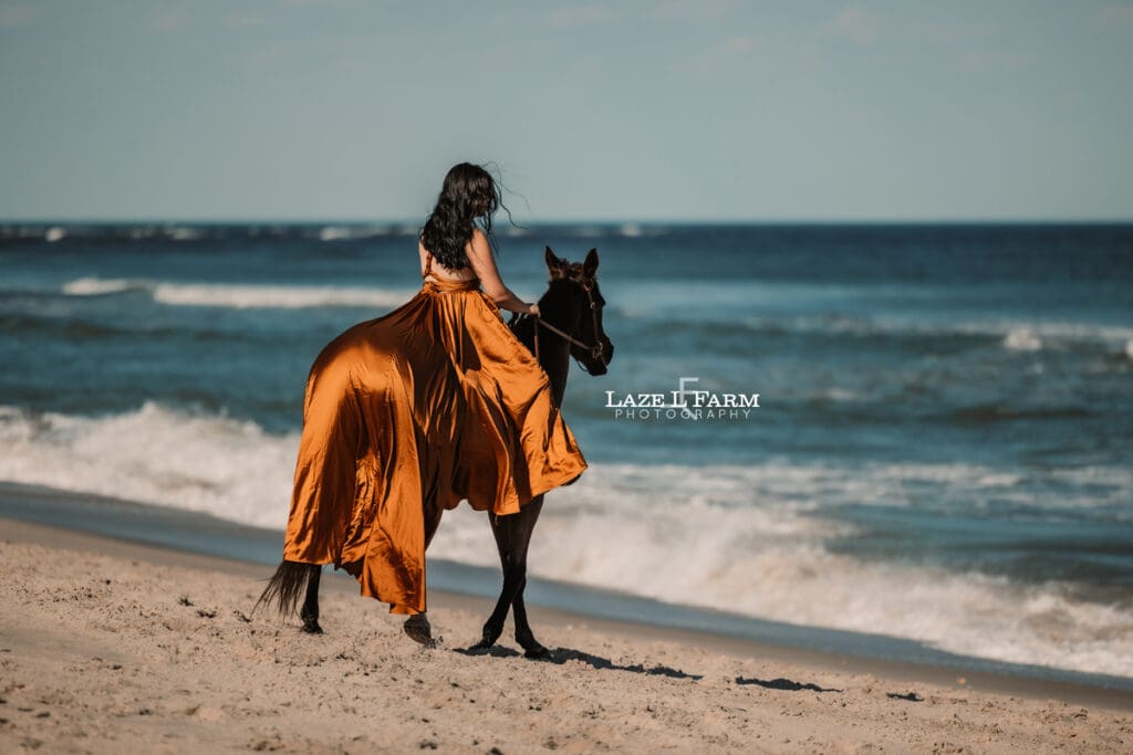 cowgirl on the beach with her horse in a flying dress