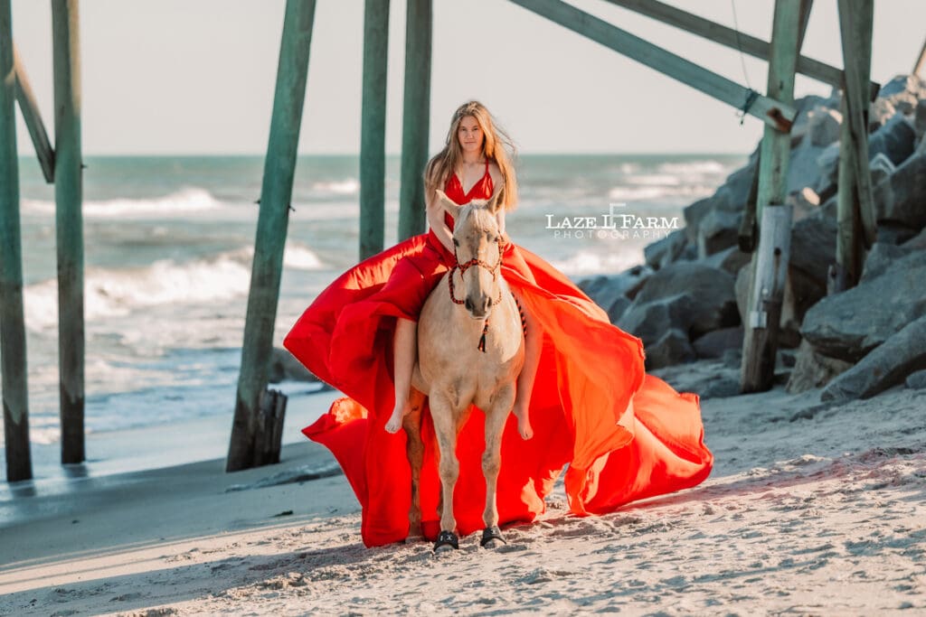 cowgirl on the beach with her horse in a flying dress