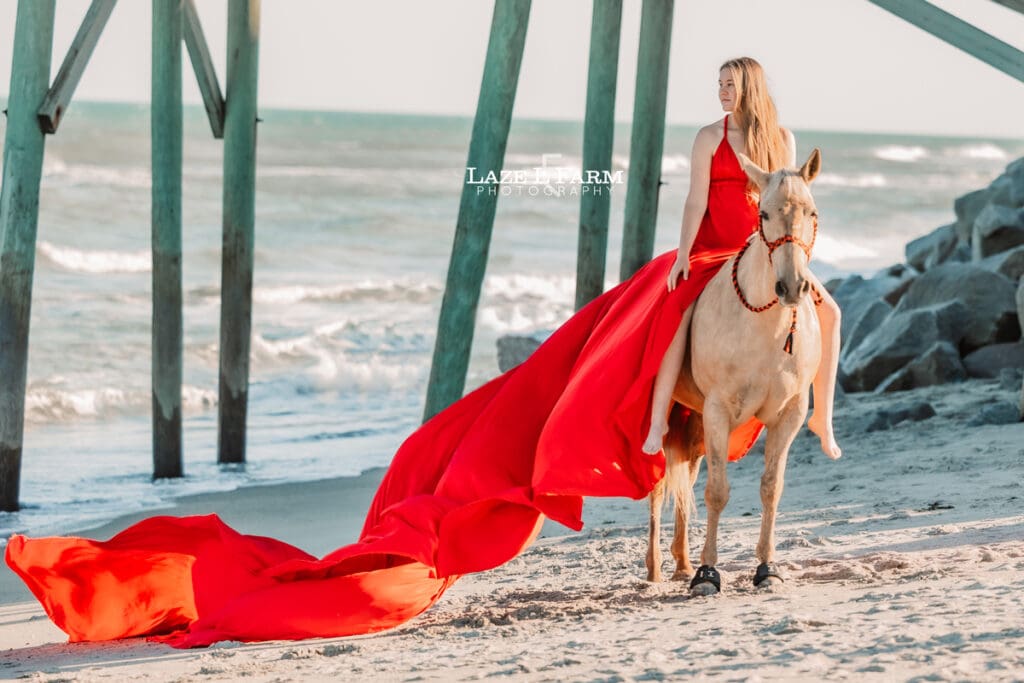 cowgirl on the beach with her horse in a flying dress