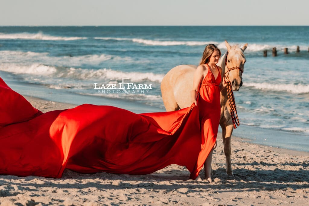 cowgirl on the beach with her horse in a flying dress