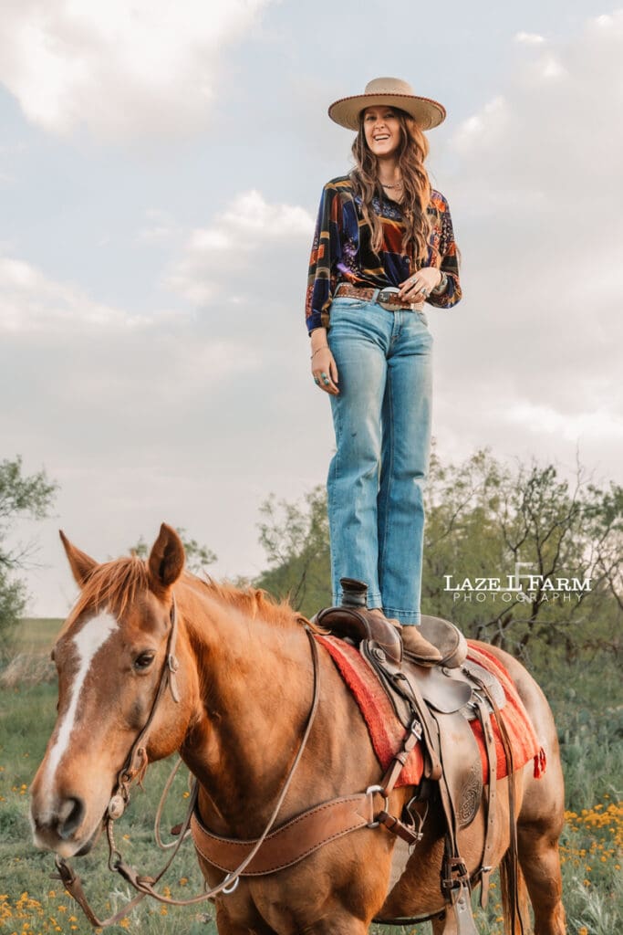cowgirl standing on her horses back