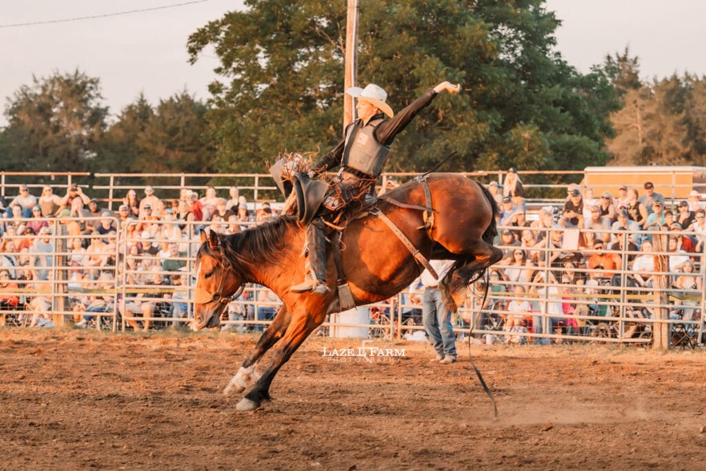 Cowboy riding a bronc at the Cleveland Rodeo while Laze L Farm Photography takes pictures