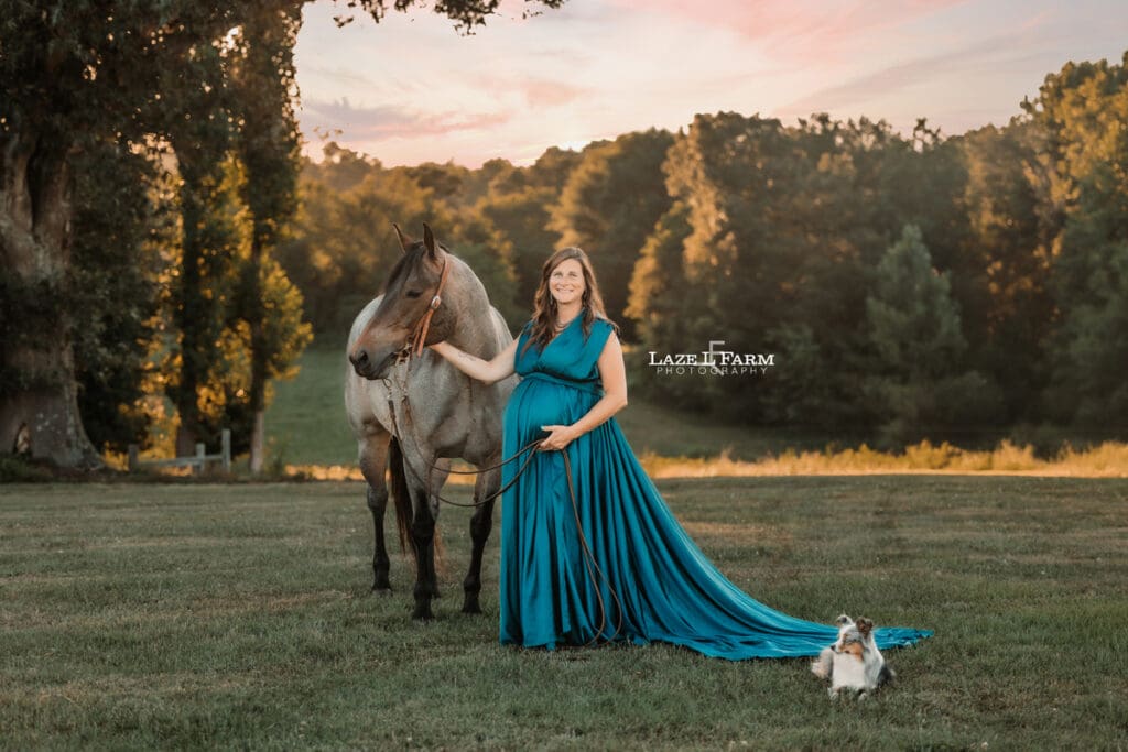 A girl standing beside her horse in a turquoise parachute dress during her maternity session with Laze L Farm Photography