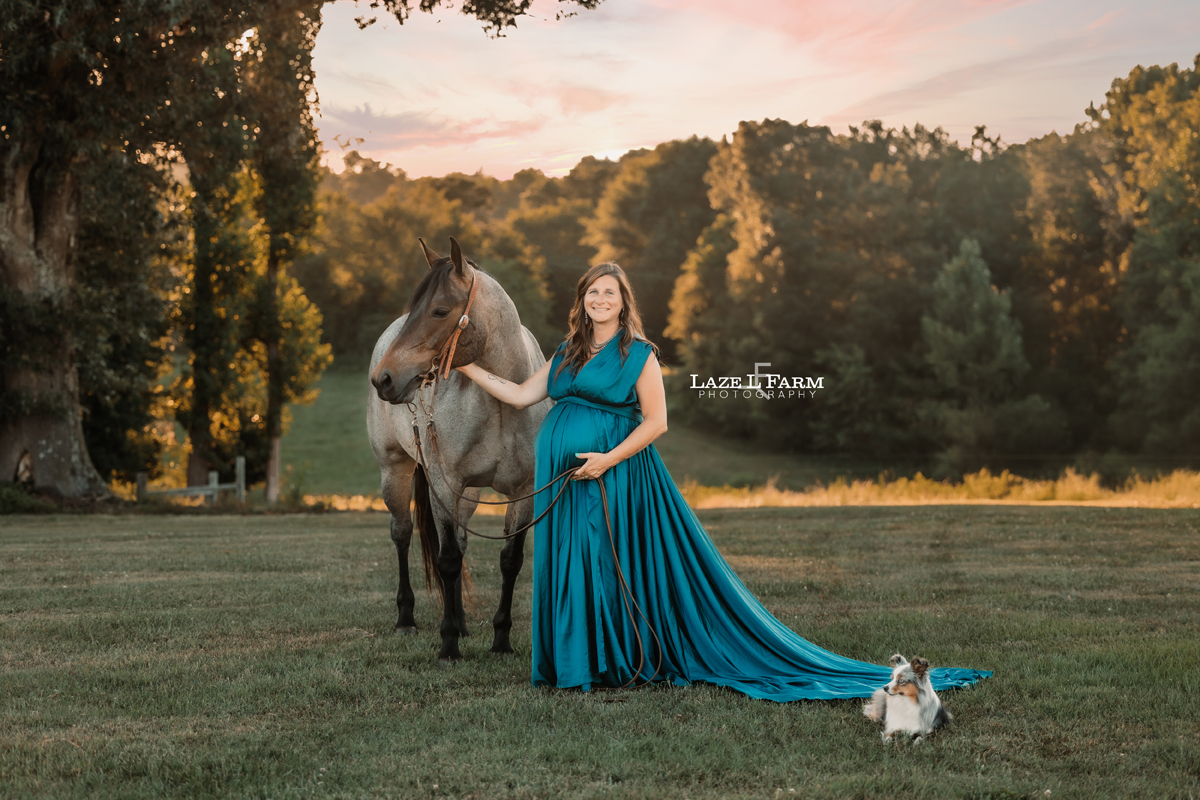 A girl standing beside her horse in a turquoise parachute dress during her maternity session with Laze L Farm Photography