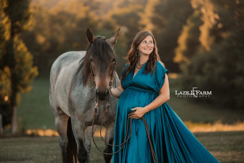 A girl standing beside her horse in a turquoise parachute dress during her maternity session with Laze L Farm Photography