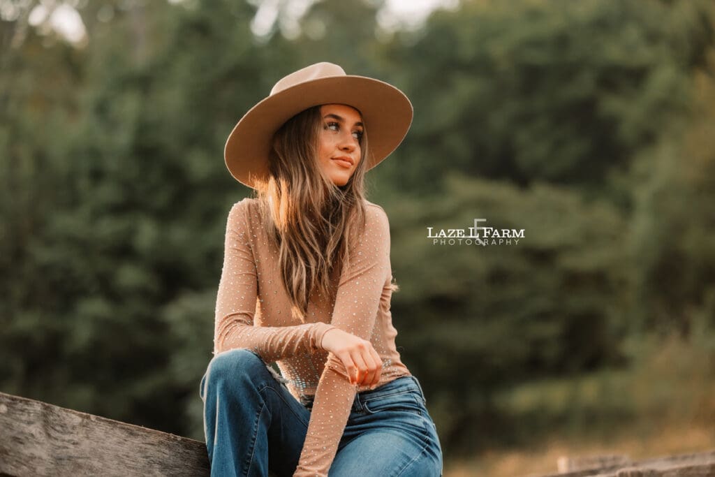 cowgirl leaning against the cattle shoot during a photoshoot with Laze L Farm Photography