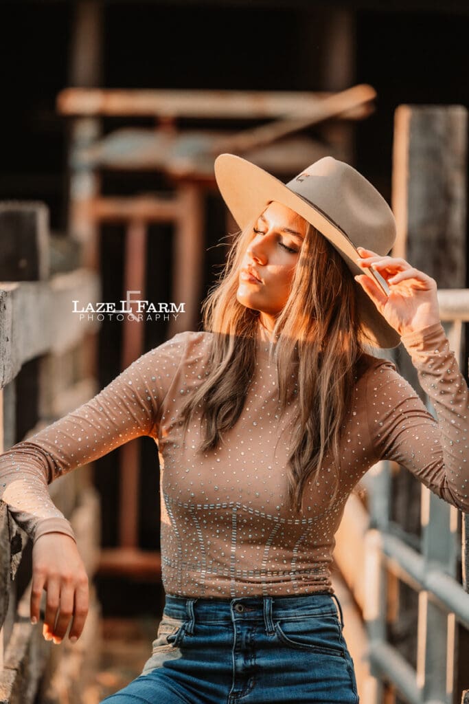cowgirl leaning against the cattle shoot during a photoshoot with Laze L Farm Photography