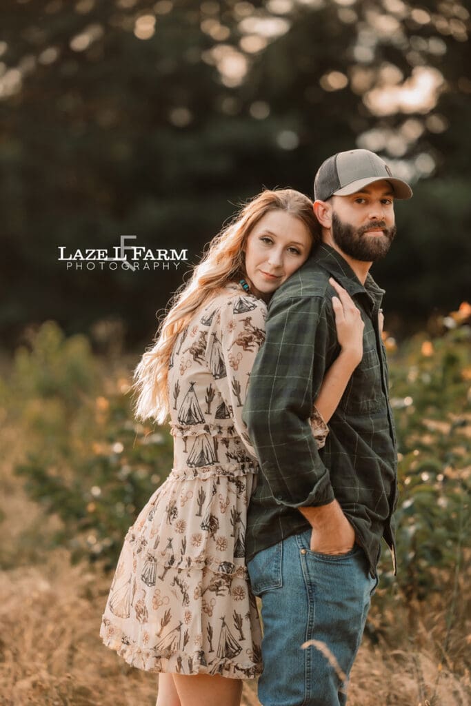 A couple during in a field holding hands at sunset during a photoshoot with Laze L Farm Photography