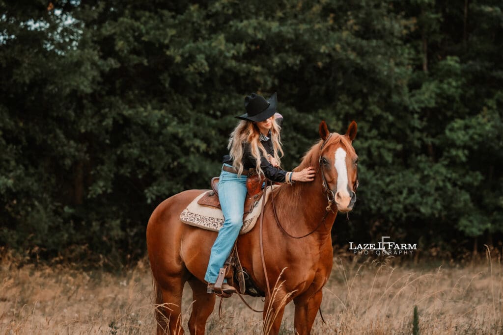 A cowgirl riding her horse in a field at sunset during a photoshoot with Laze L Farm Photography