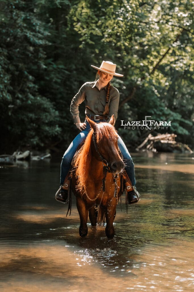 Cowgirl riding her horse horse in the creek during a photoshoot with Laze L Farm Photography