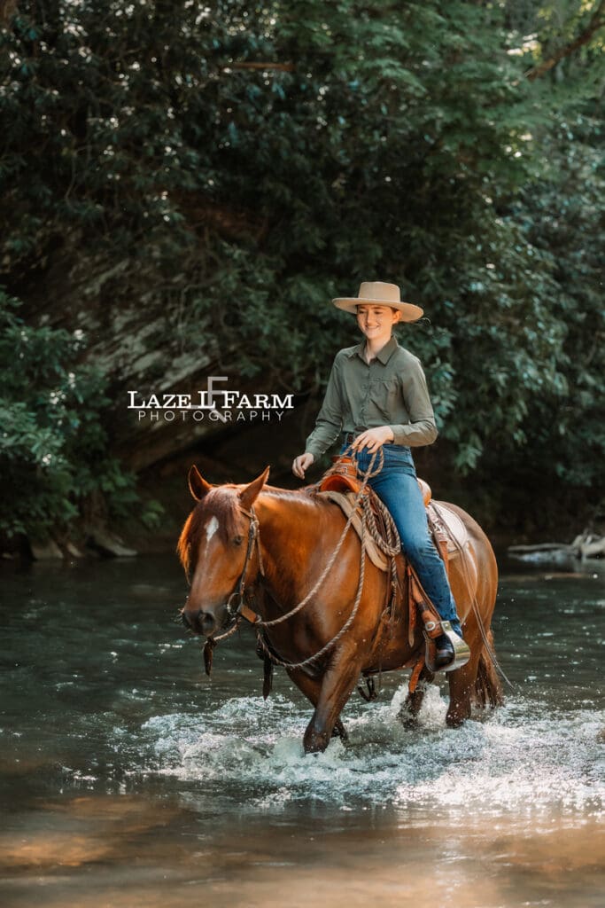 Cowgirl riding her horse horse in the creek during a photoshoot with Laze L Farm Photography