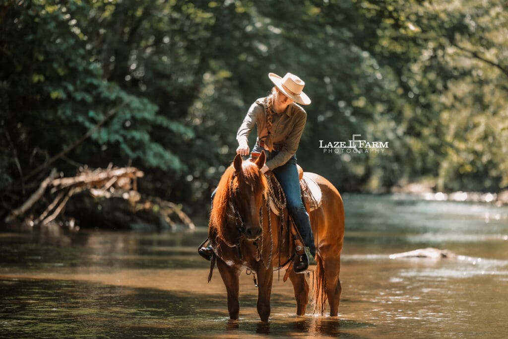 Cowgirl riding her horse horse in the creek during a photoshoot with Laze L Farm Photography