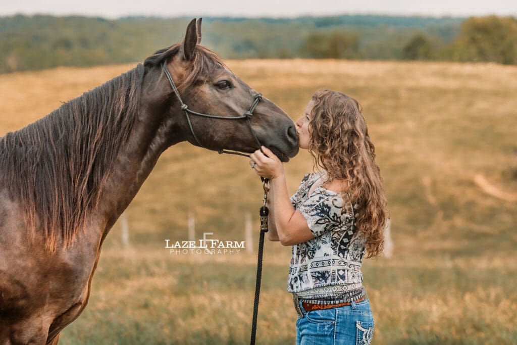 A girl kissing her horse in a field during a photoshoot with Laze L Farm Photography