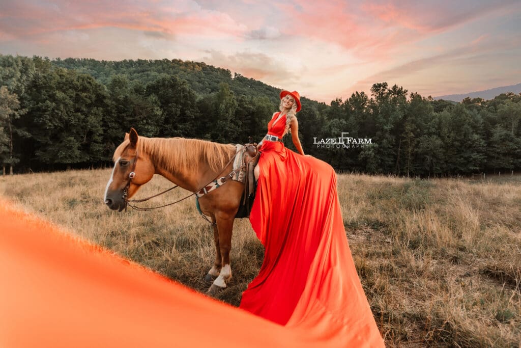 a girl in a red parachute dress at sunset with a horse in a field during a photoshoot with Laze L Farm Photography in Taylorsville NC